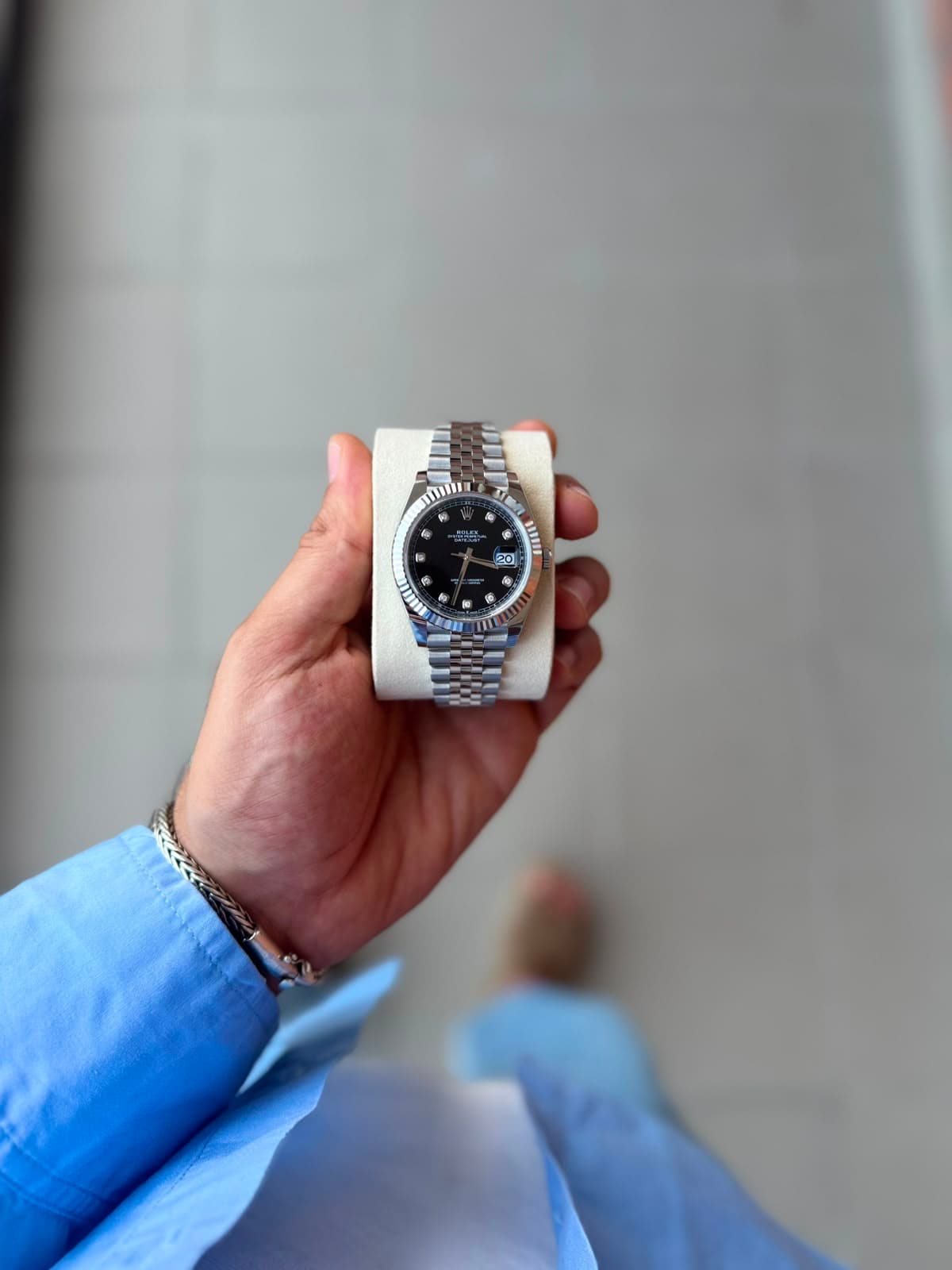 Rolex Datejust black dial against a gray tile wall