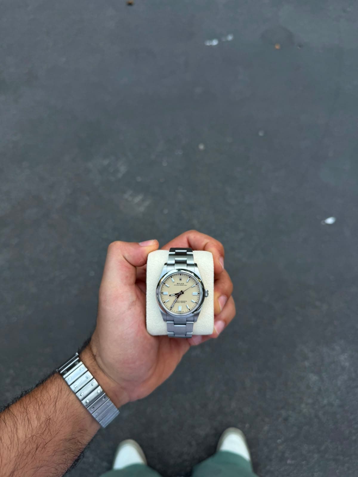 Rolex Oyster Perpetual cream dial on dark wet asphalt