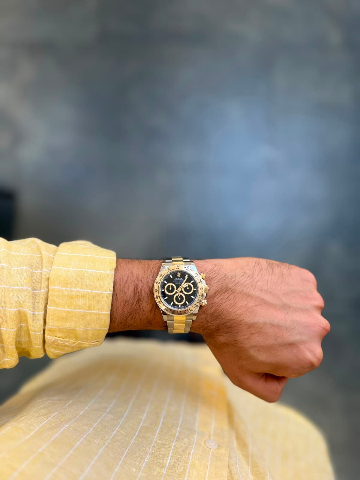 Two-tone Rolex Daytona against a soft gray-blue wall
