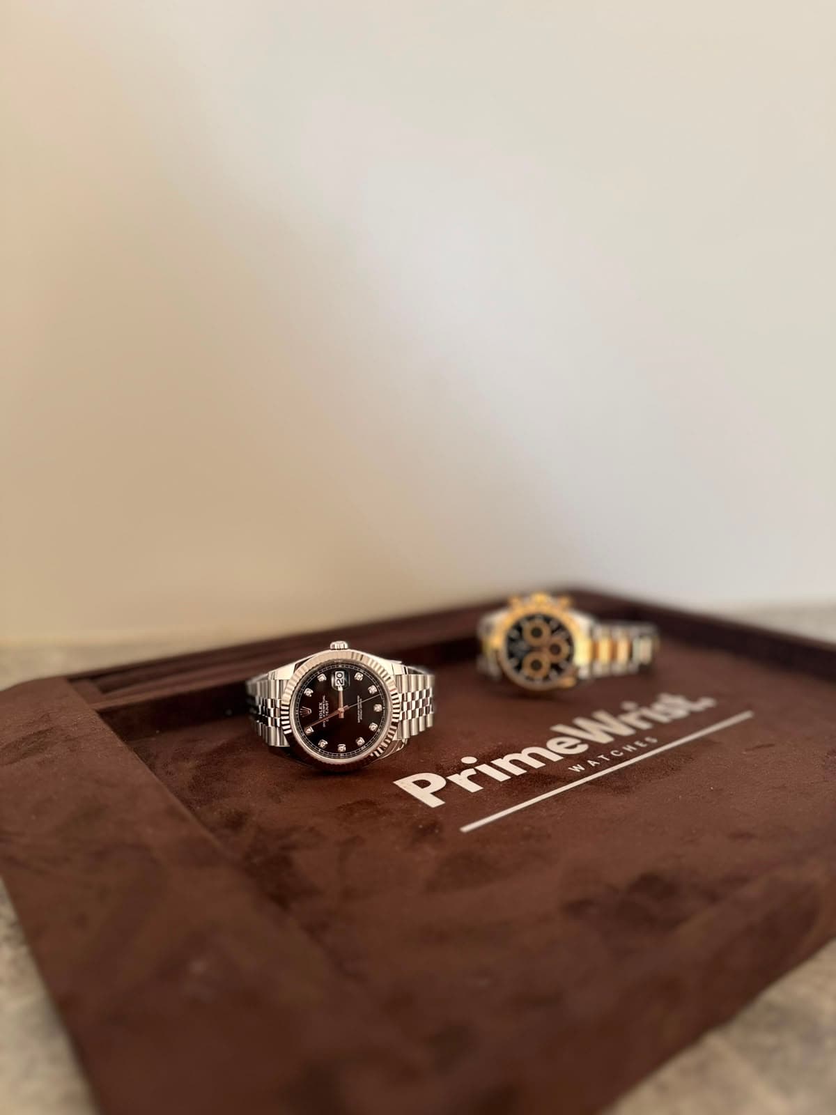 Two PrimeWrist watches presented on a branded suede tray