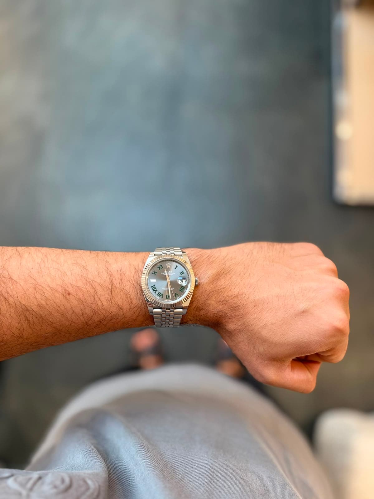 Rolex Datejust with green Roman-numeral dial against a muted wall